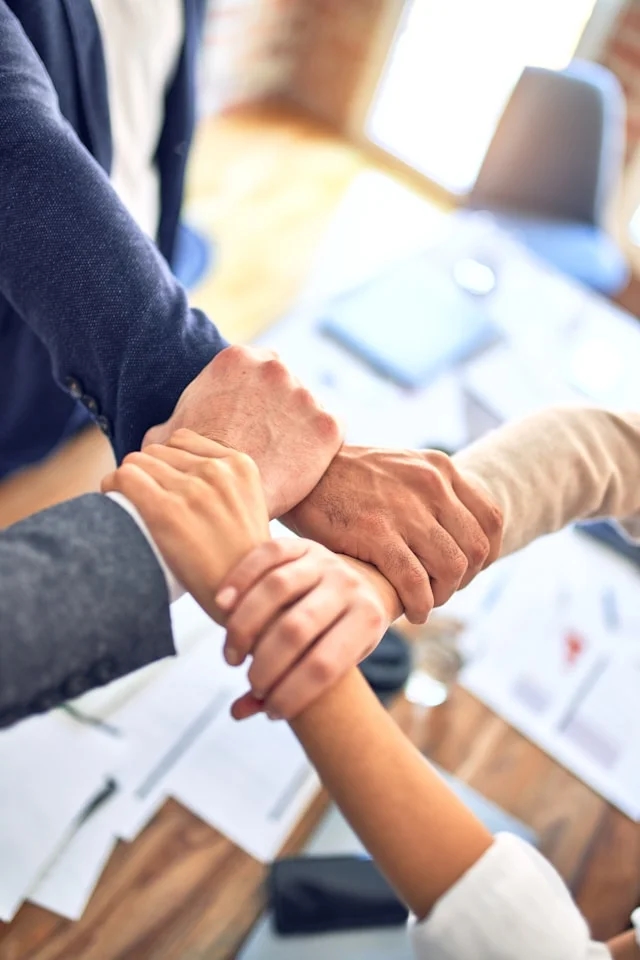 Advisers linking hands over a desk of case documents at the Belgrade office